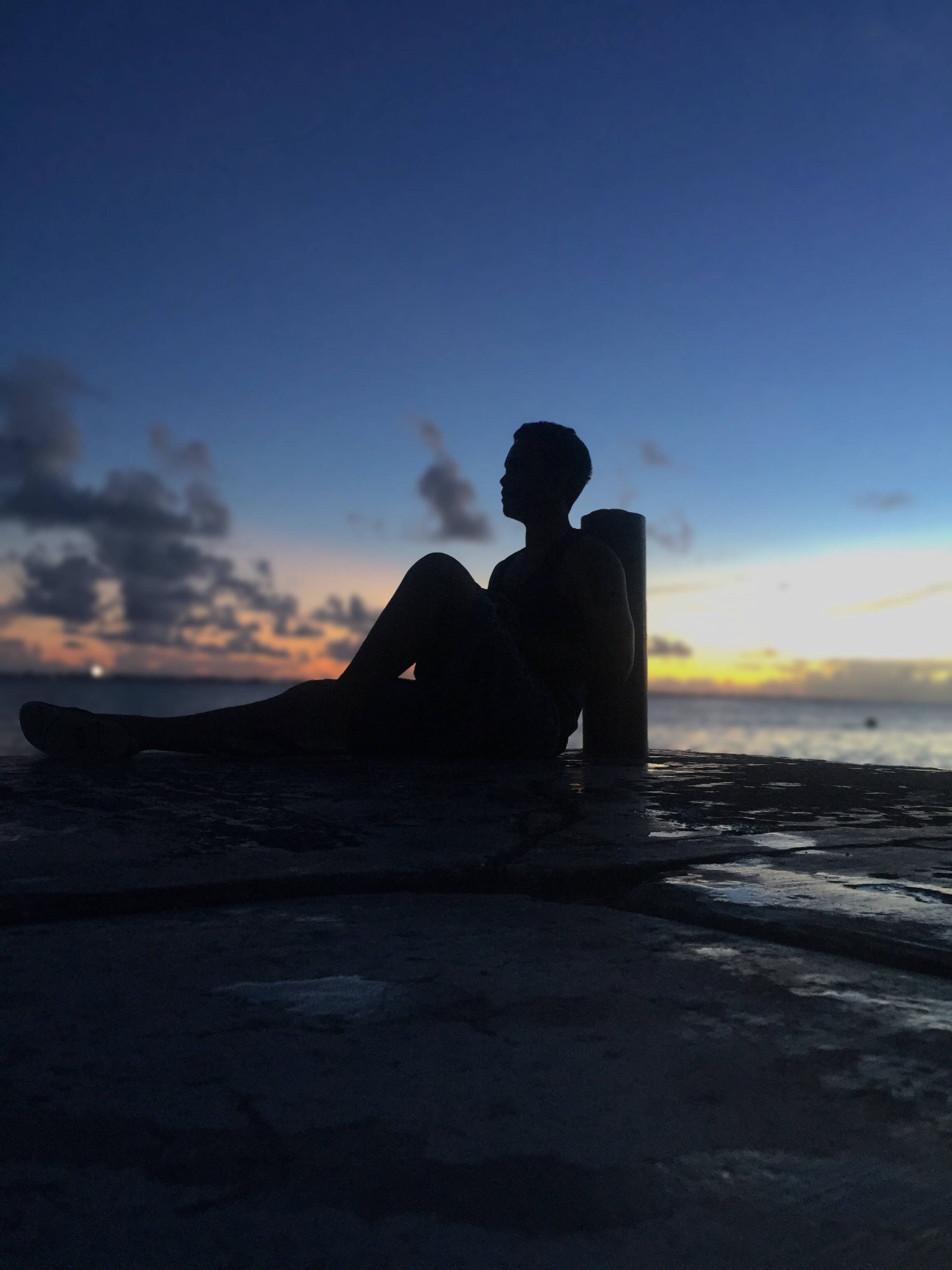 Marshall Island 桌布 壁紙 — 一個人的剪影，在黃昏時獨自坐在碼頭上，背後是充滿活力的橙色和藍色天空。