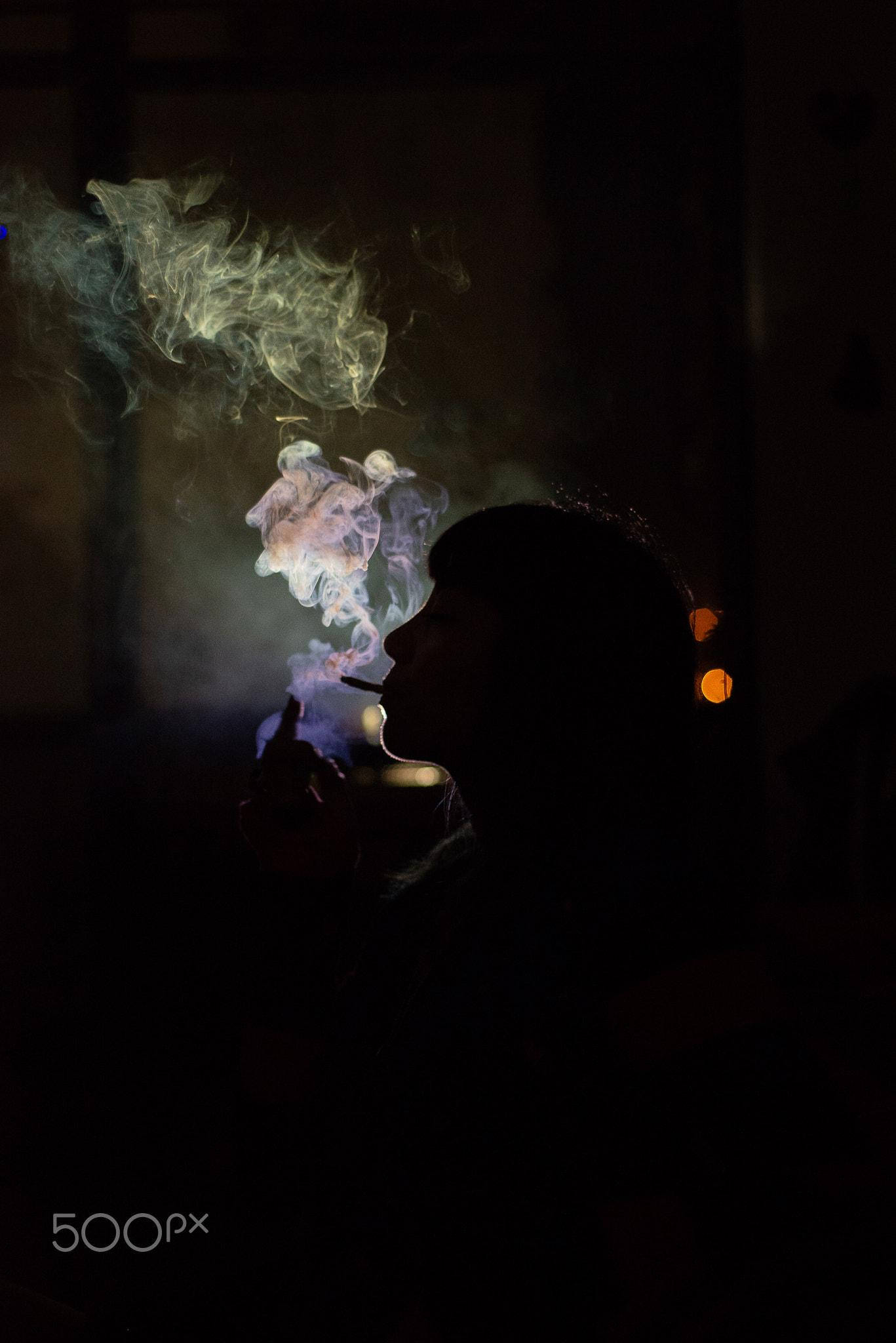 Blunt 桌布 壁紙 — 一個人的剪影，在黑暗背景中呼出鮮豔旋轉的煙霧，伴隨著溫暖的散景燈光。