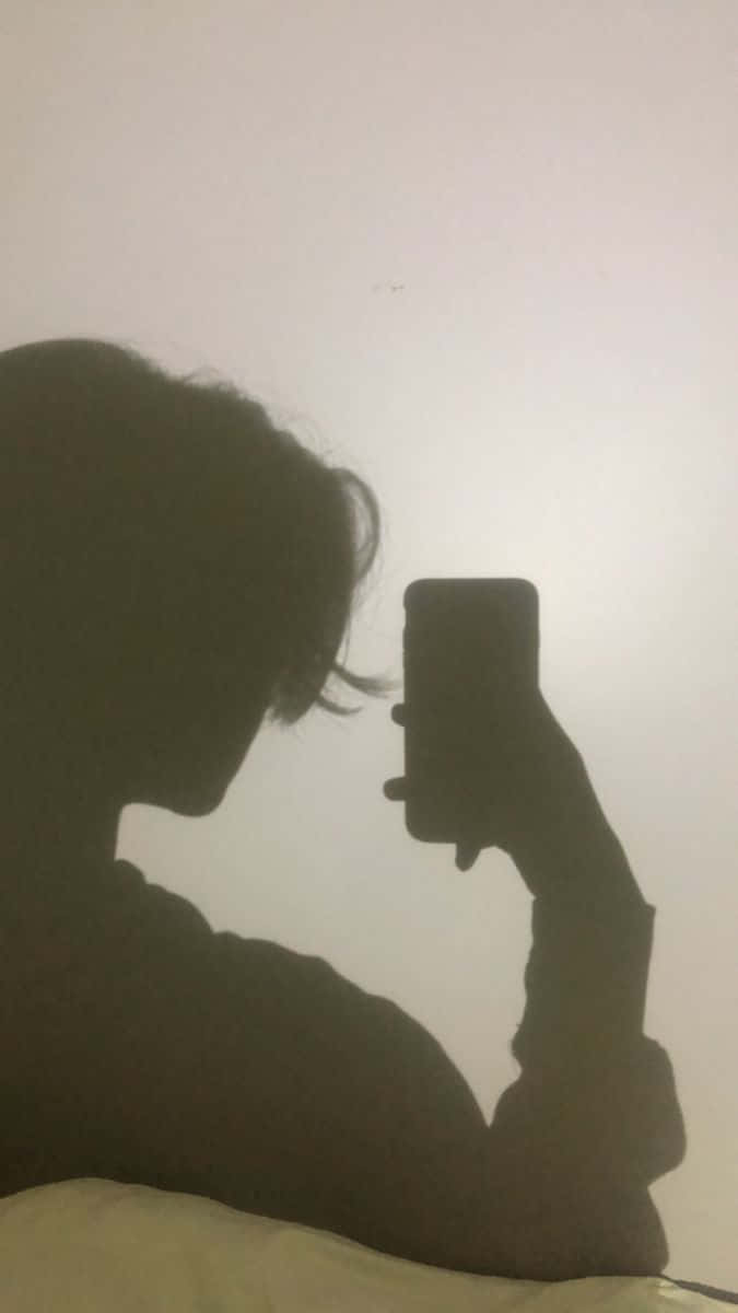 shadow 桌布 壁紙 — 一個人的剪影，拿著電話在普通牆前面自拍。