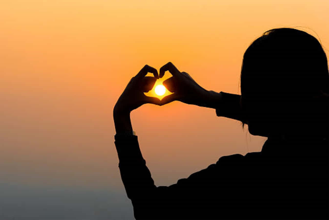 Heart Silhouette 桌布 壁紙 — 一個人的剪影，雙手圍繞著發光的夕陽形成心形。