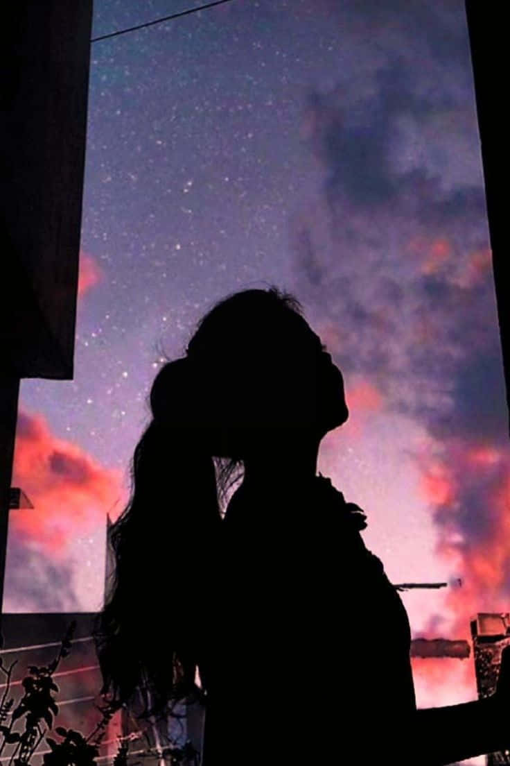 Aesthetic Cute Profile 桌布 壁紙 — 一個人的剪影仰望星空，天空被紫色和火熱的橙色雲彩塗抹成暮色。