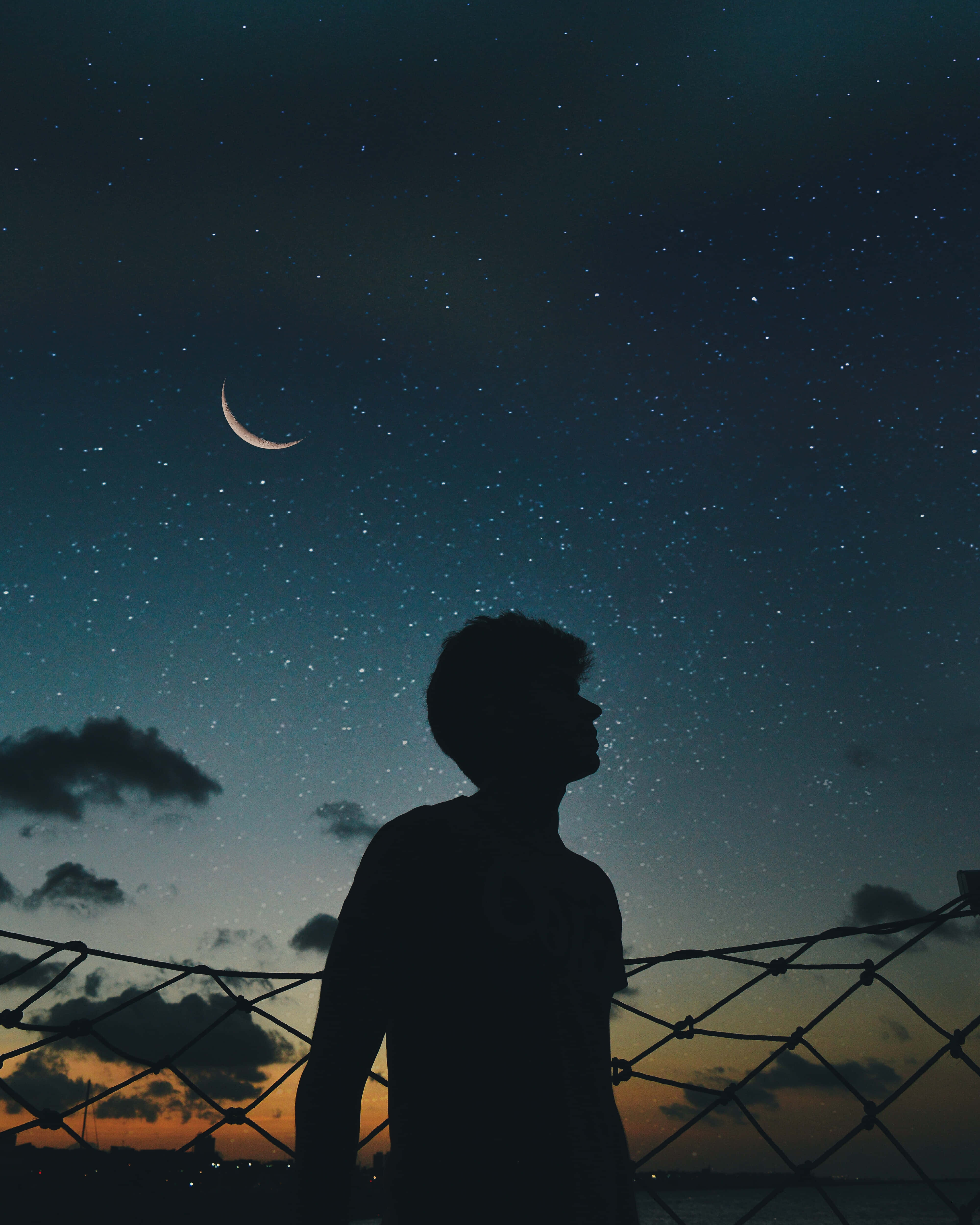 Silhouette 桌布 壁紙 — 一個人的剪影仰望被鐵絲網圍欄框住的彎月和星空。