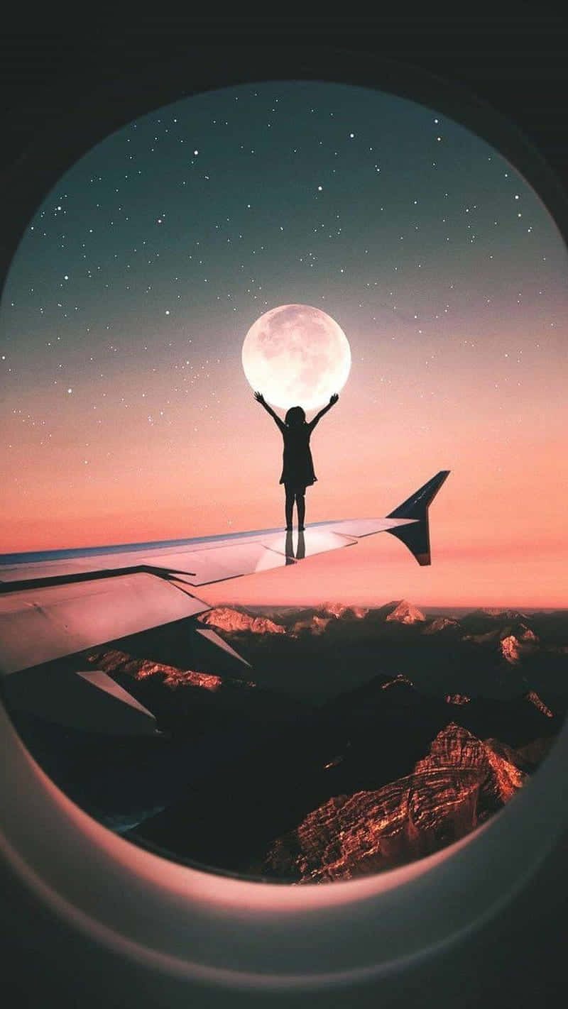 手機 桌布 壁紙 — 一個人的剪影勝利地站在飛機機翼上，在繁星點點的暮色天空中伸手觸摸發光的月亮。