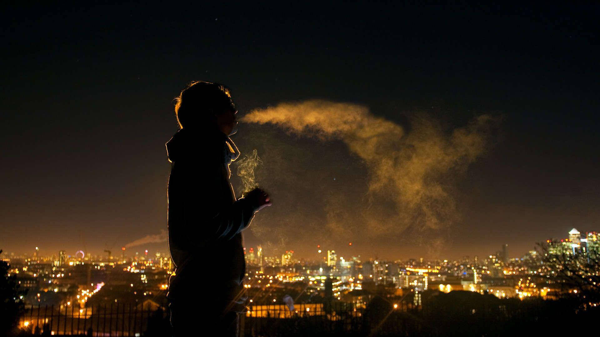 lights 桌布 壁紙 — 一個人的剪影在夜晚對著充滿活力的城市天際線呼出溫暖的蒸氣。