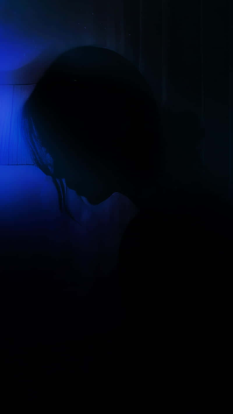 桌布 壁紙 — 一個人的剪影在深沉的陰影中，被清冷的藍光照亮，映在紋理牆壁上，喚起孤獨和靜默的沉思。
