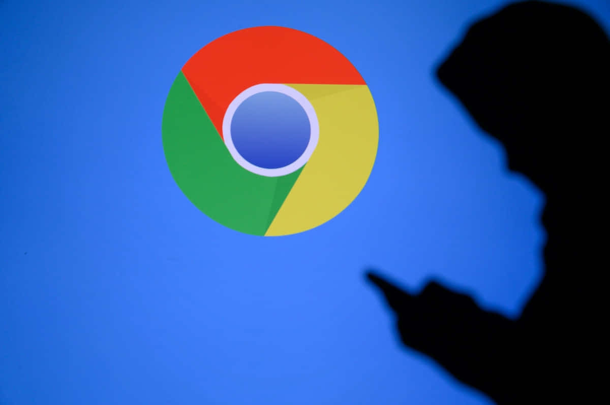 Chrome 桌布 壁紙 — 一個人的剪影在藍色螢幕上發光的Chrome瀏覽器標誌前拿著手機。