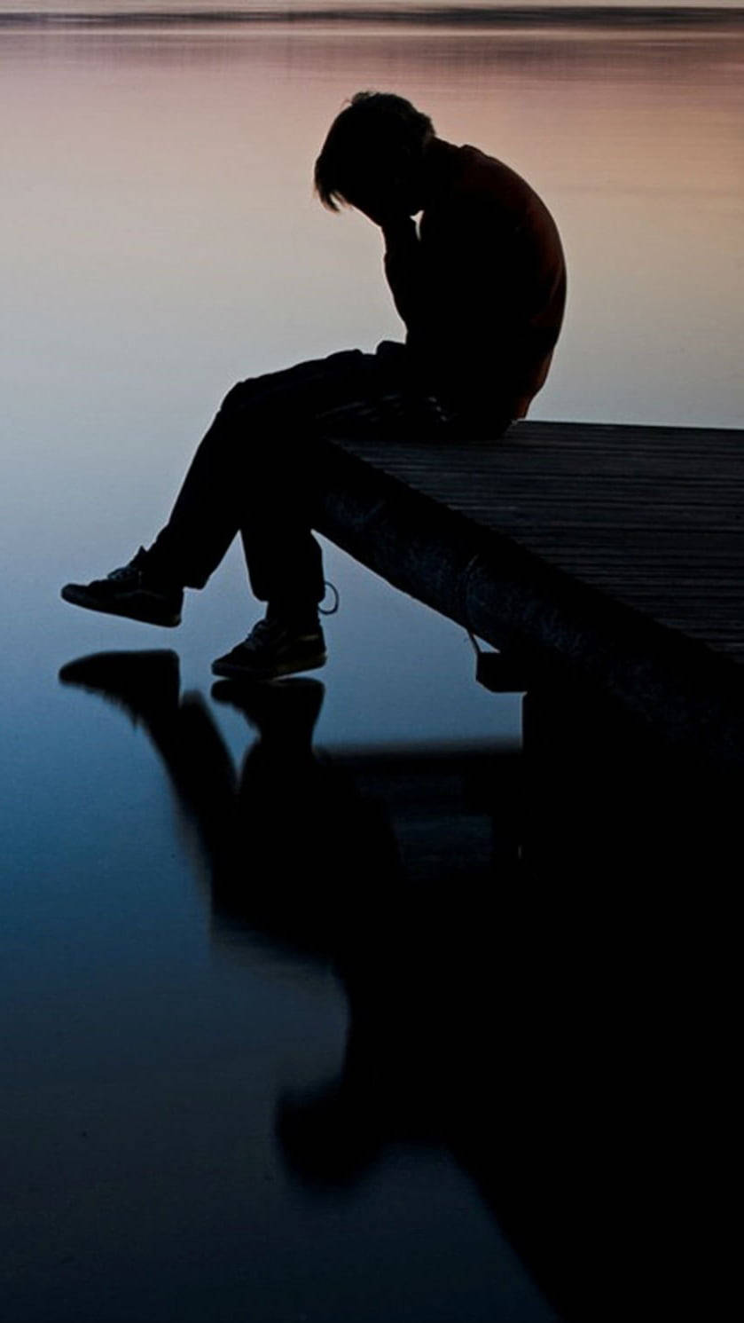 Depression Aesthetic 桌布 壁紙 — 一個人的剪影在黃昏時獨自坐在碼頭上，倒影映在平靜的水面上。