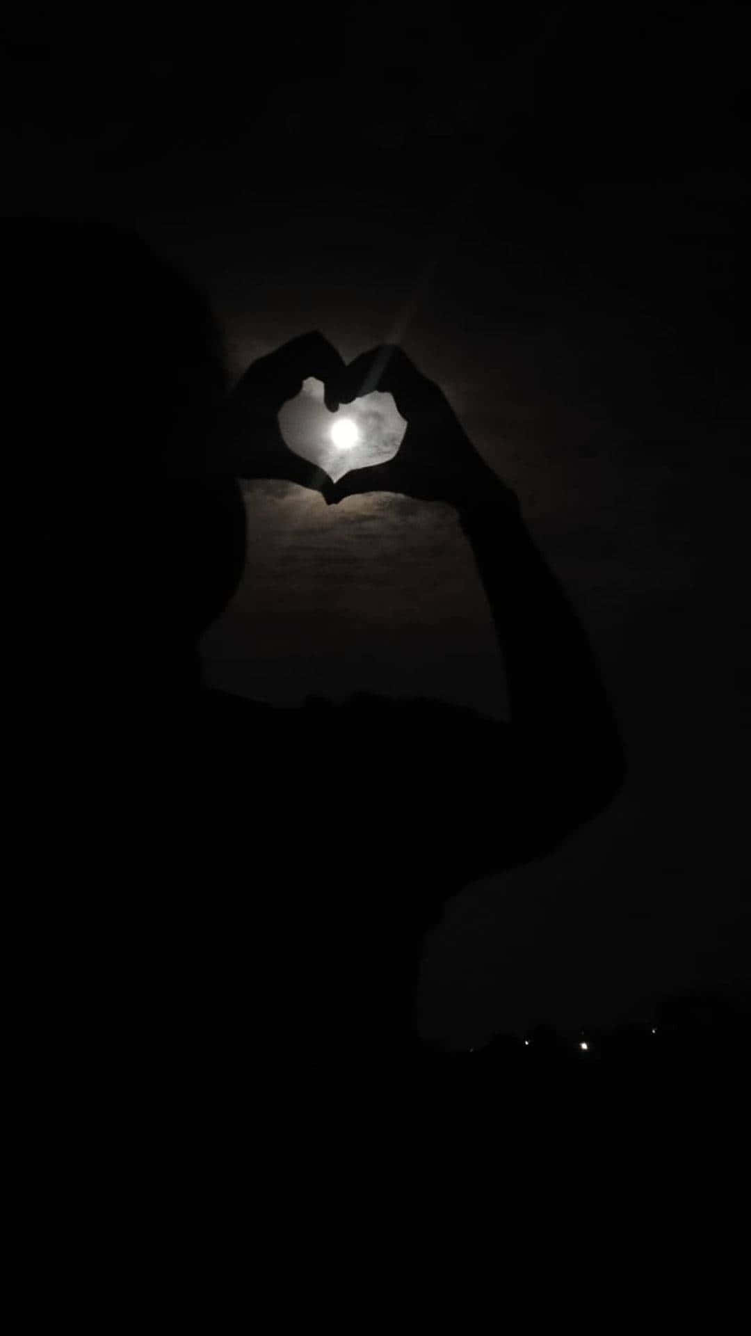 Aesthetic Black 桌布 壁紙 — 一個人的剪影在黑暗的夜空下，用雙手形成心形環繞著發光的月亮。