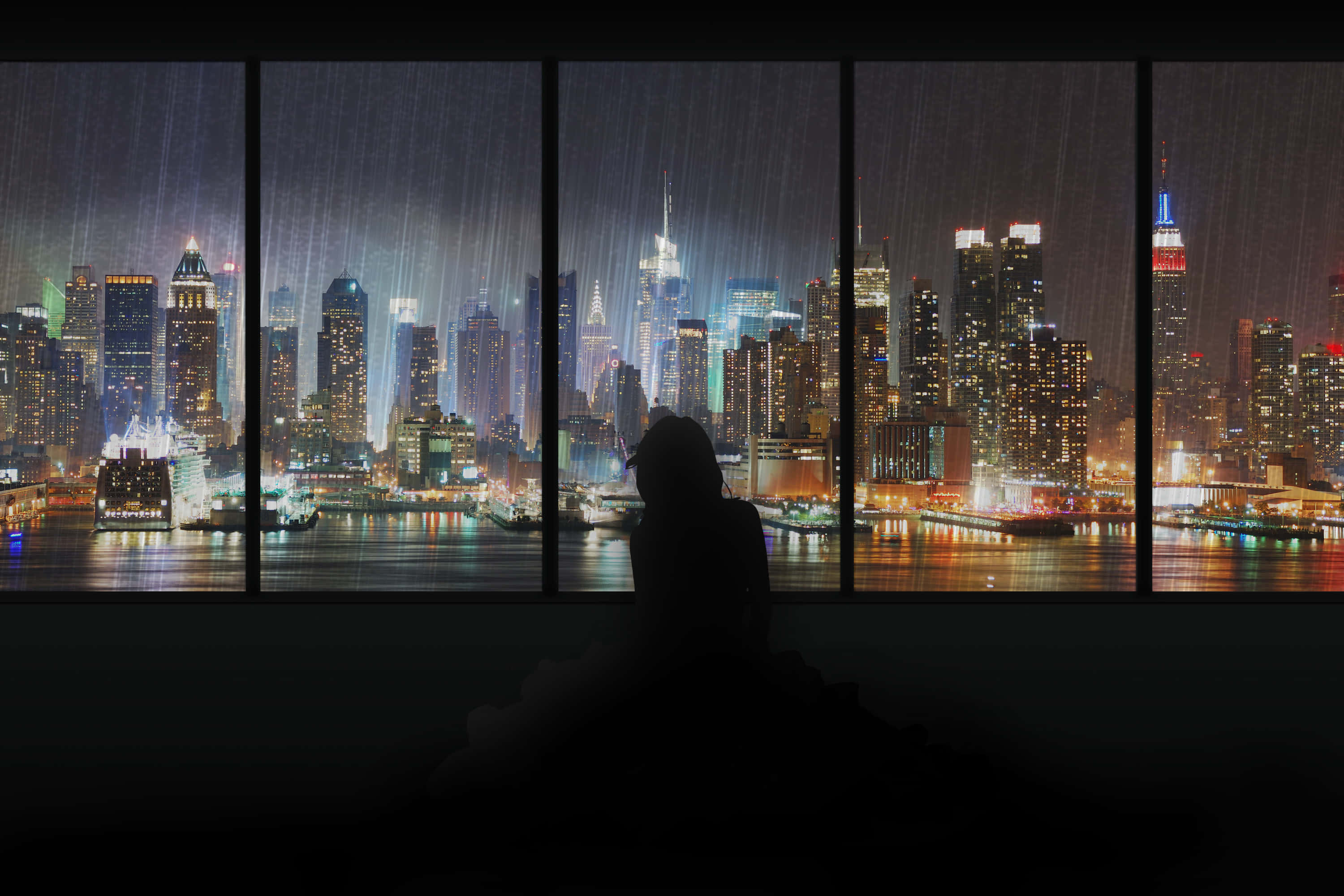 Aesthetic Anime City 桌布 壁紙 — 一個人的剪影坐在有雨痕的窗邊，俯瞰夜晚充滿活力的霓虹燈城市景觀。