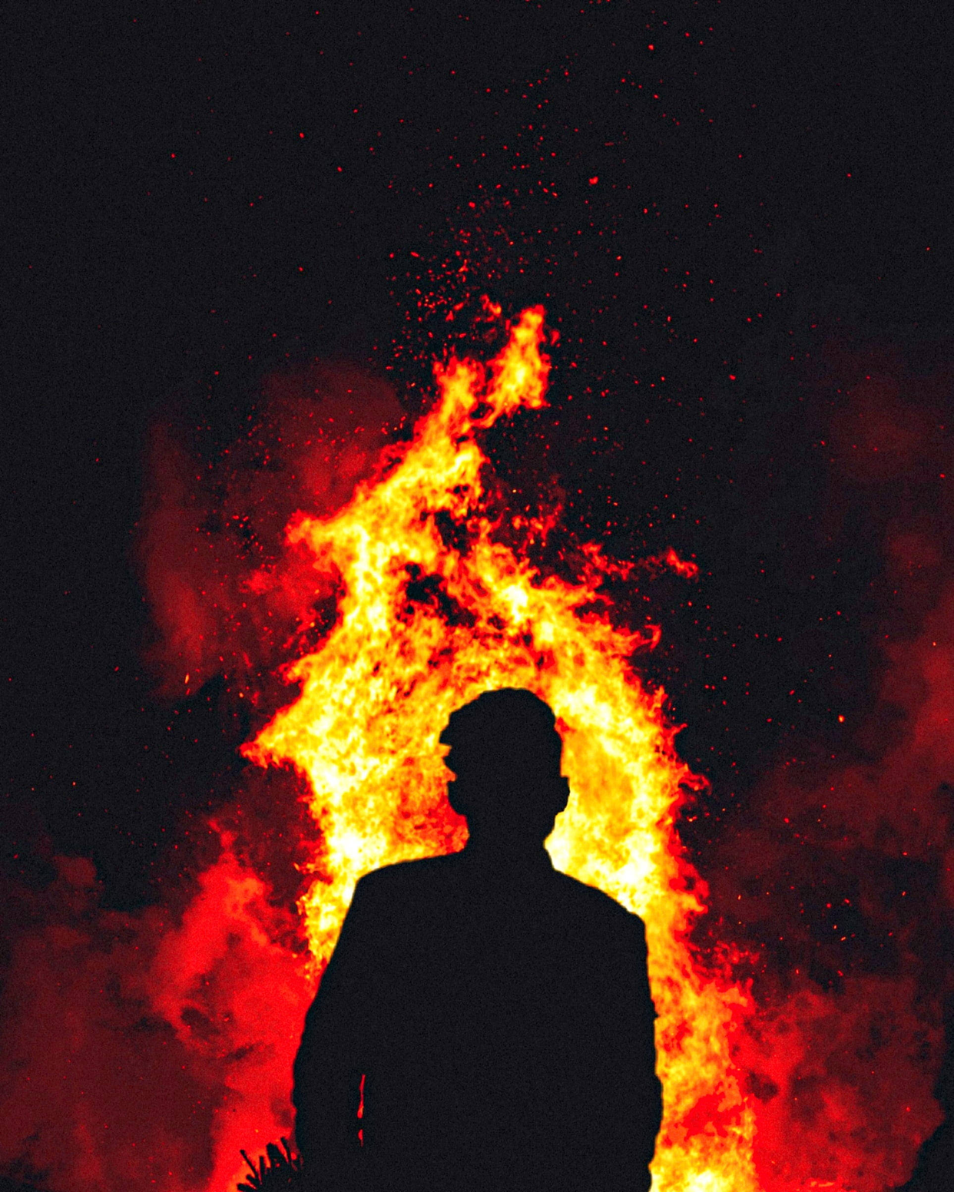 Man 桌布 壁紙 — 一個人的剪影站在熊熊烈火前，火花在黑暗的夜空中飛舞。