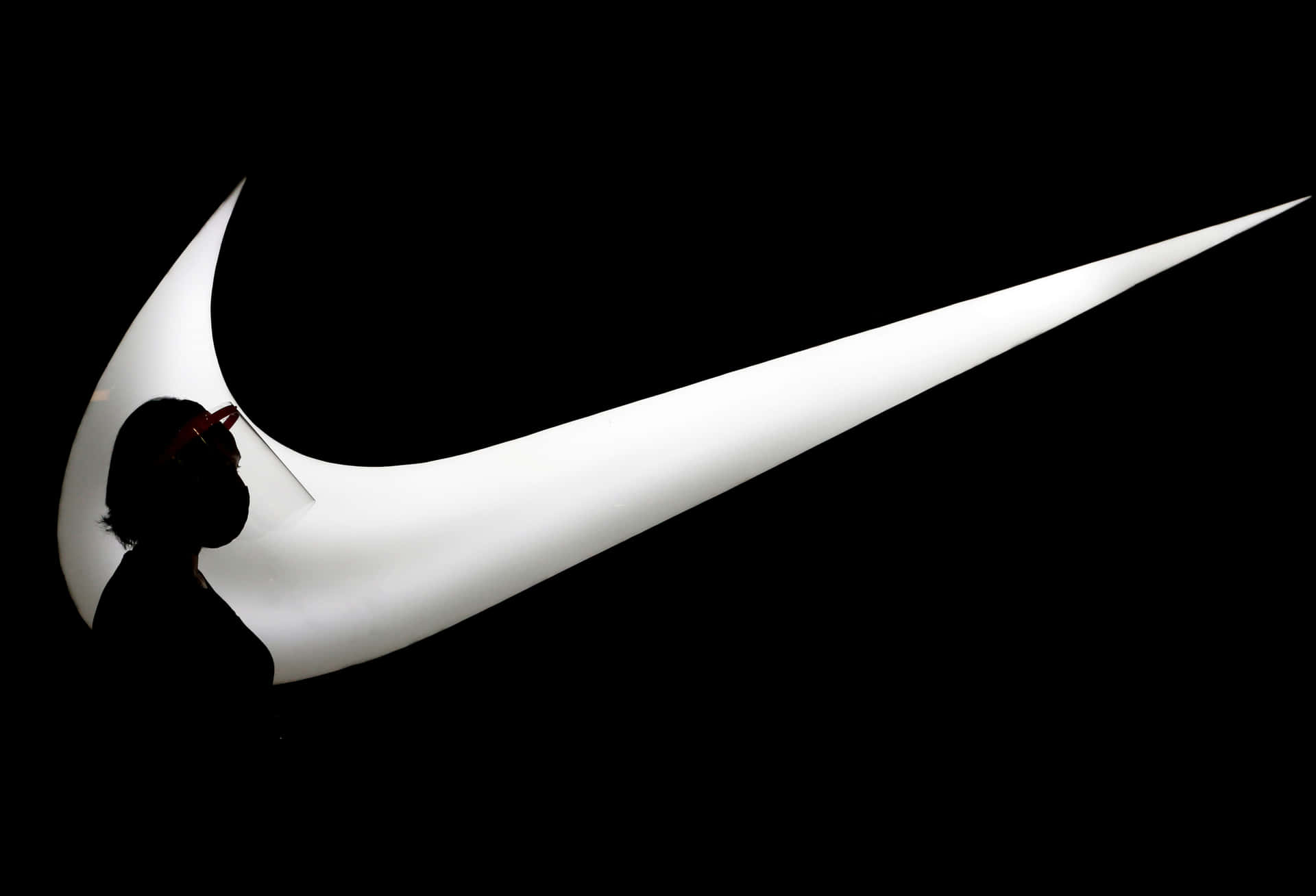 一個人在發光的Nike標誌前的剪影。 — Nike GIF 壁紙