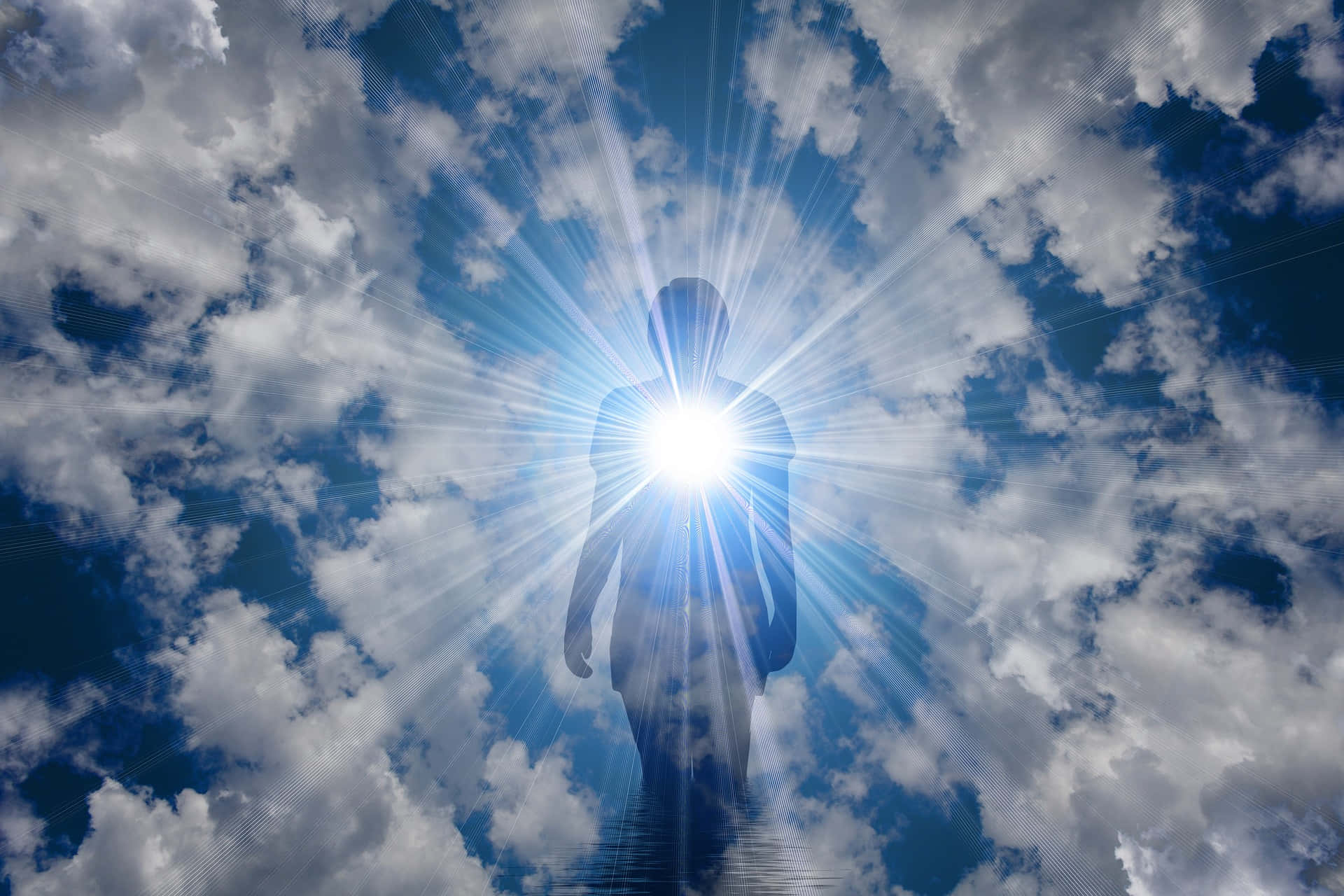 Spirituality 桌布 壁紙 — 一個人的燦爛剪影，站在明亮的陽光爆發中，陽光穿過蓬鬆的白雲，映襯在生動的藍天上。