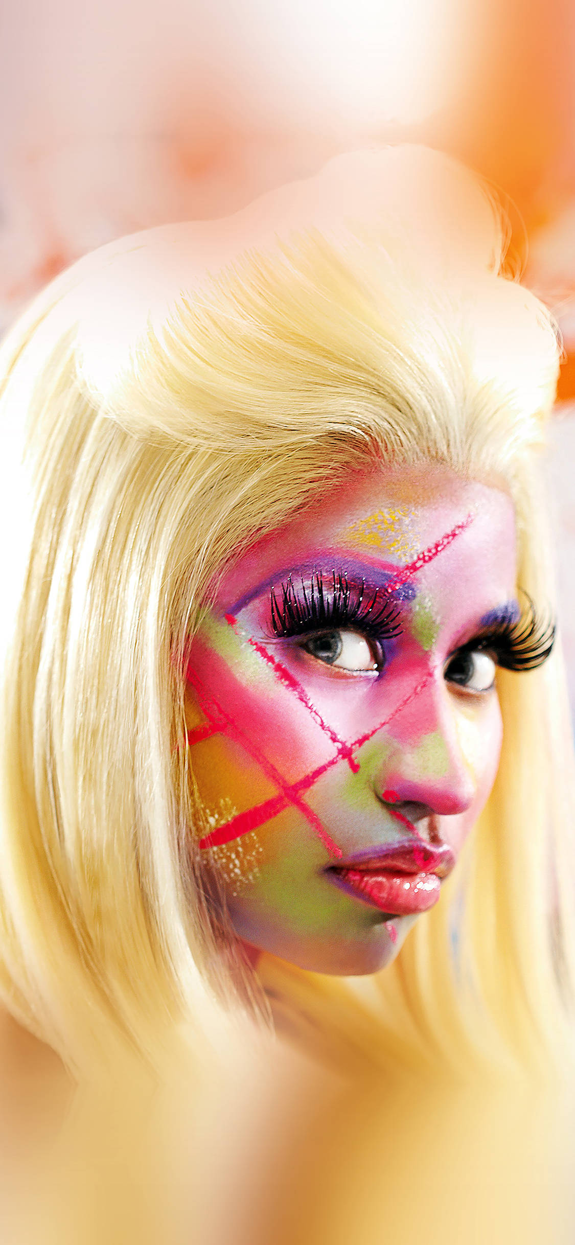 Nicki 桌布 壁紙 — 一個人的特寫肖像，帶有鮮豔大膽的化妝和金髮，背景溫暖模糊。