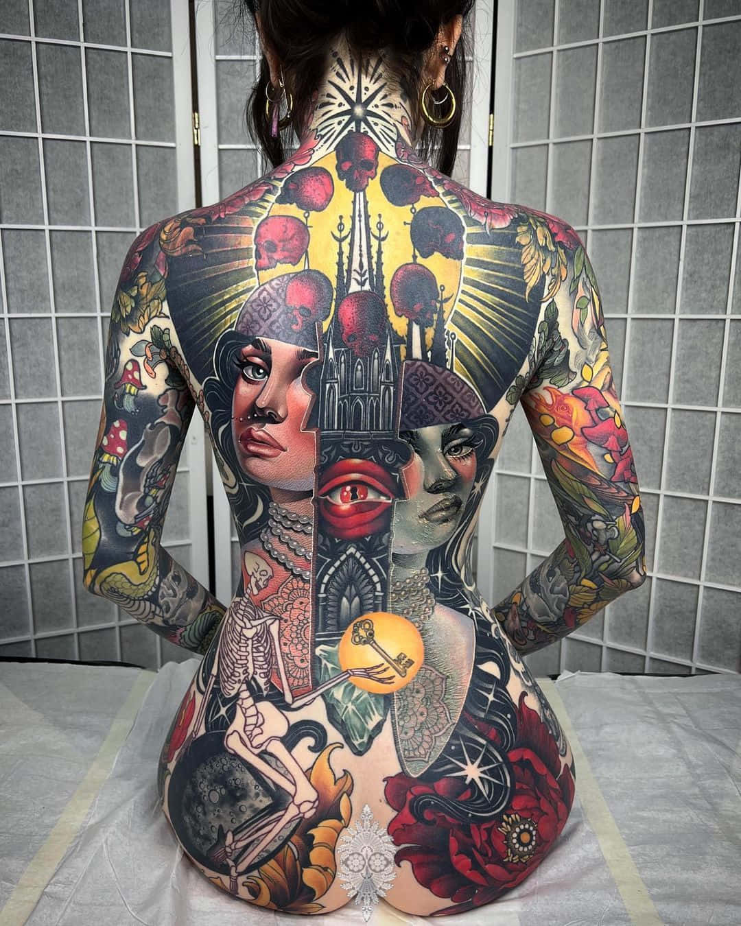 Tattoo Girl 桌布 壁紙 — 一個人的背部佈滿精細多彩的刺青，圖案包括骷髏頭、玫瑰、眼睛和哥德式建築，背景是磁磚牆。