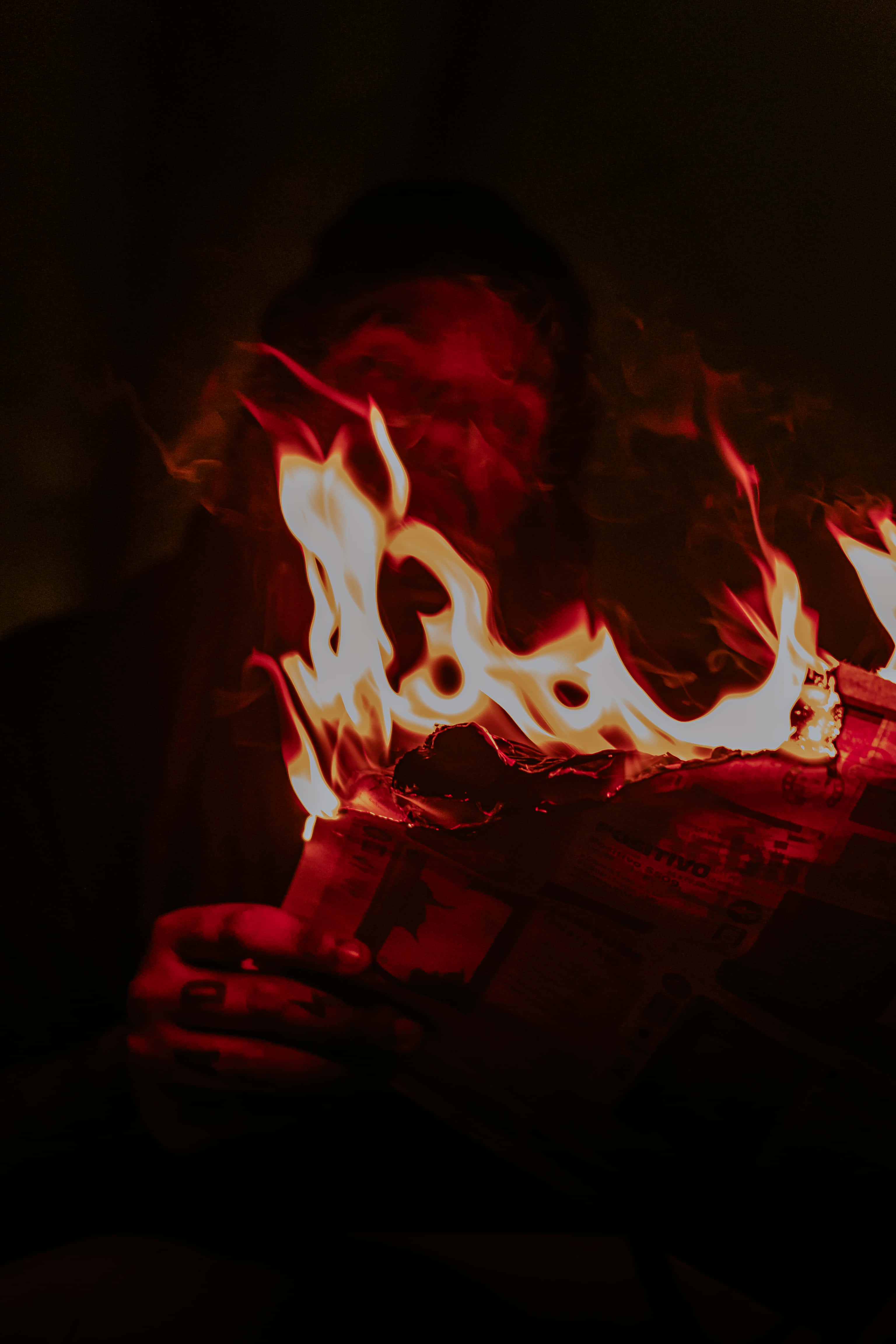 Red Fire 桌布 壁紙 — 一個人的臉被吞噬報紙的咆哮火焰遮蓋，處於黑暗而強烈的環境中。