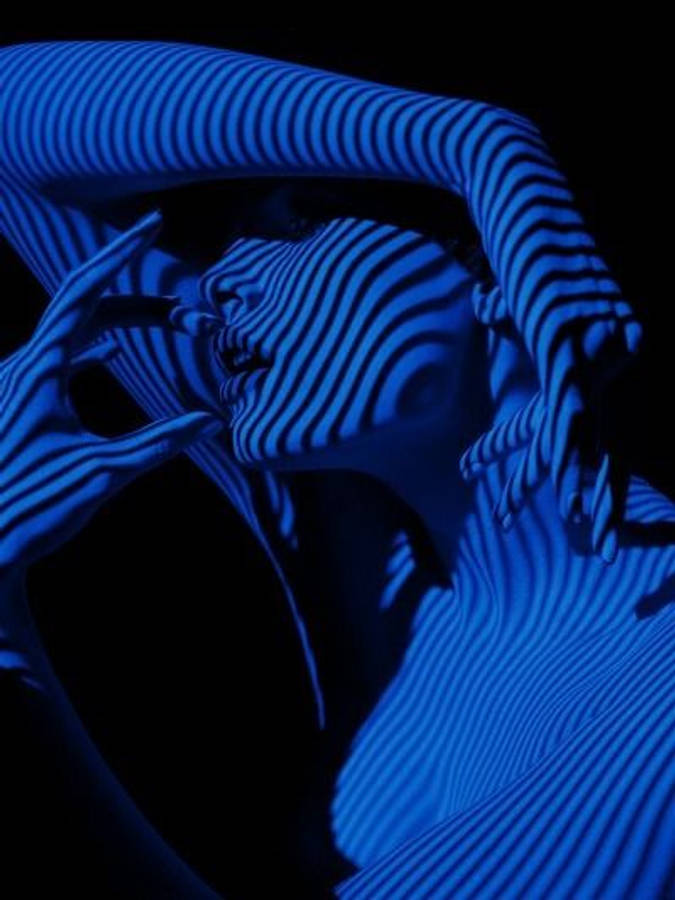 dark blue aesthetic tumblr 桌布 壁紙 — 一個人的臉部和手臂沐浴在強烈的藍光中，大膽的垂直條紋在黑色背景上營造出催眠、超現實的效果。