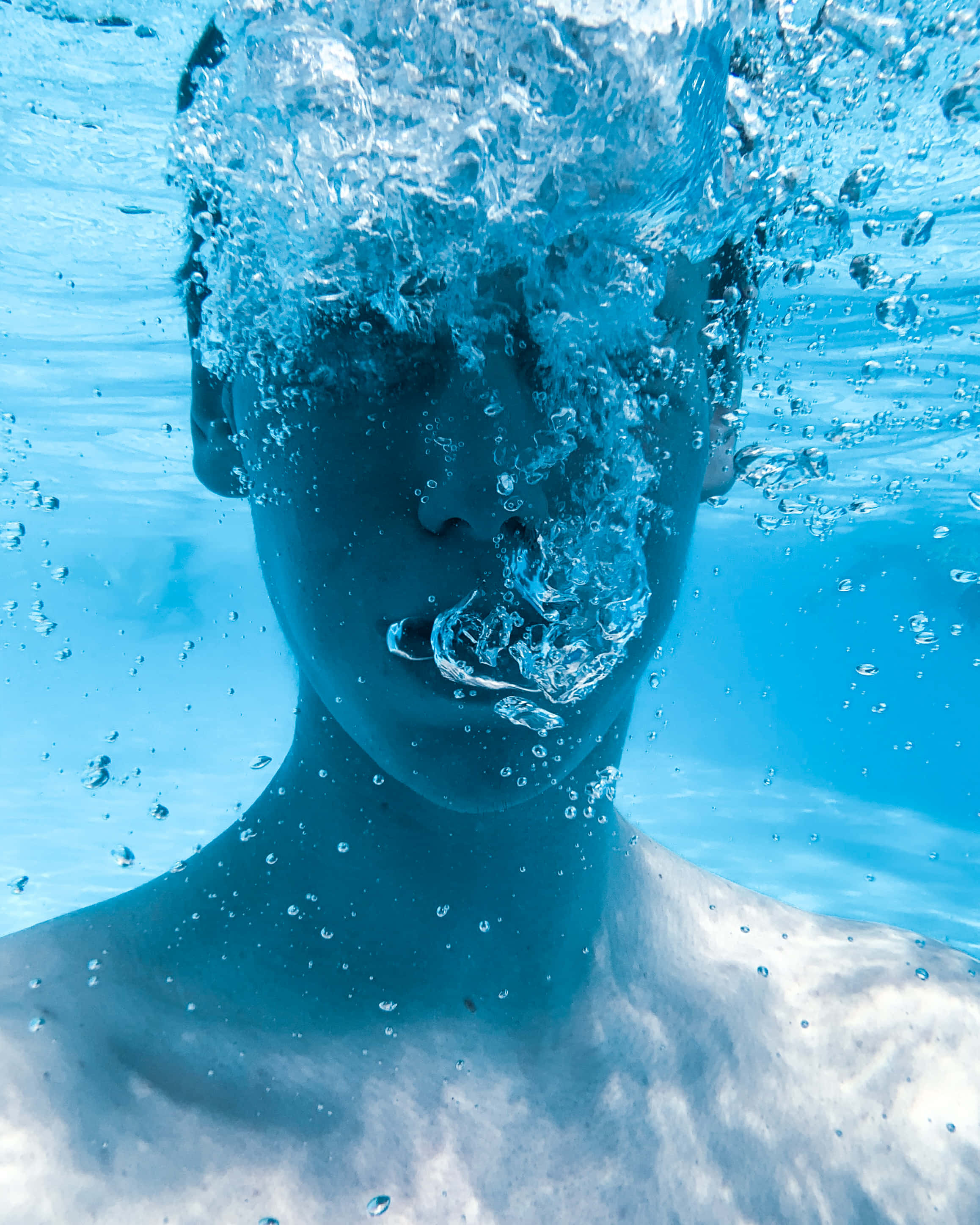 水下動畫 桌布 壁紙 — 一個人的臉部浸沒在水下，氣泡在清澈的藍色水中旋轉。