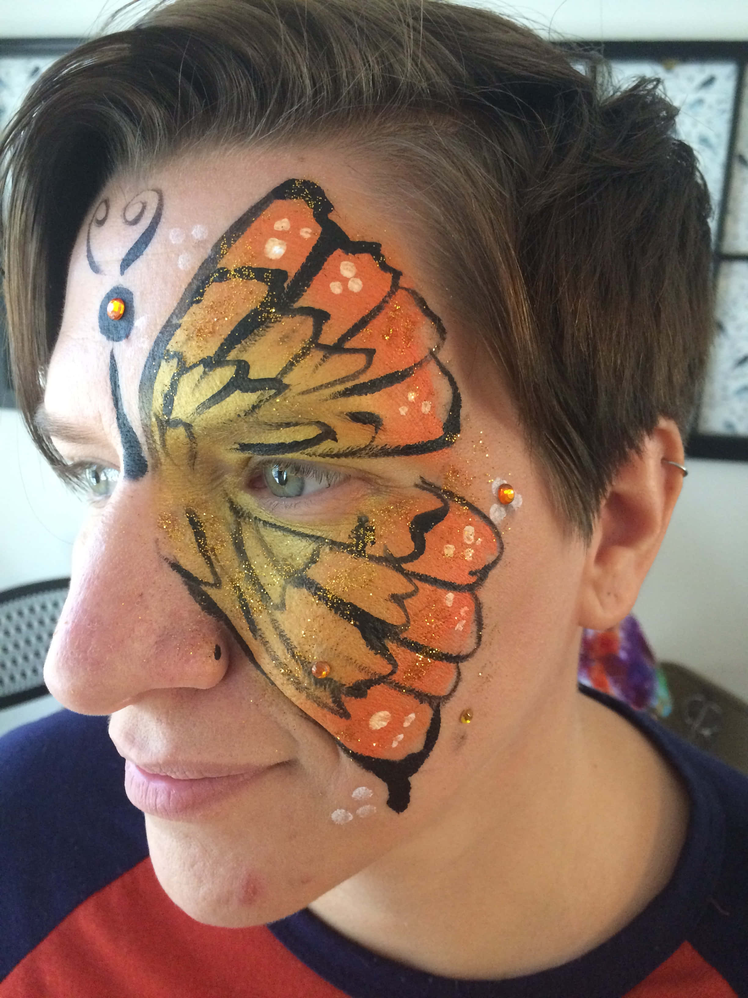 Butterfly Face Painting 桌布 壁紙 — 一個人的臉龐飾以鮮豔的橙色和黃色蝴蝶臉部彩繪，並帶有亮粉和寶石點綴。