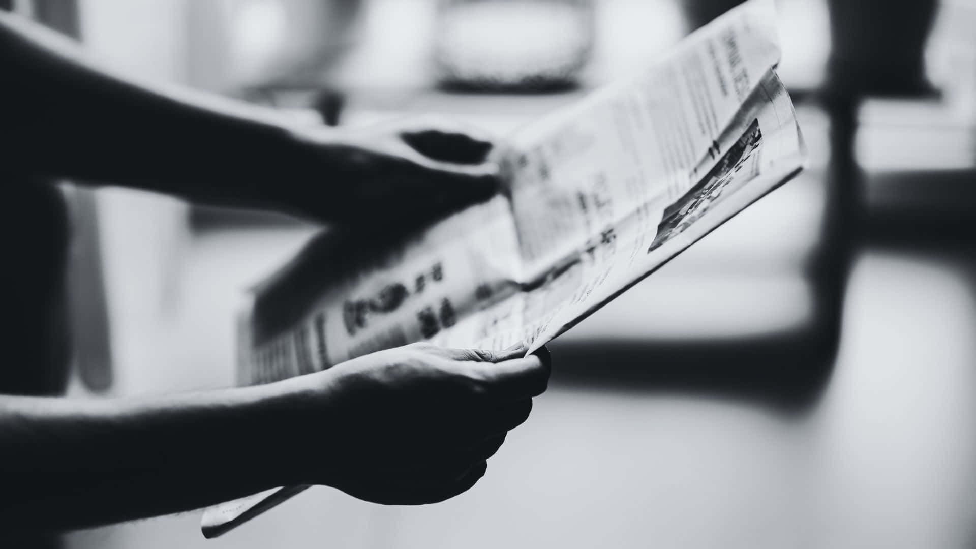 Black And White Newspaper 桌布 壁紙 — 一個人的雙手拿著並翻閱報紙，照片為淺景深黑白風格。