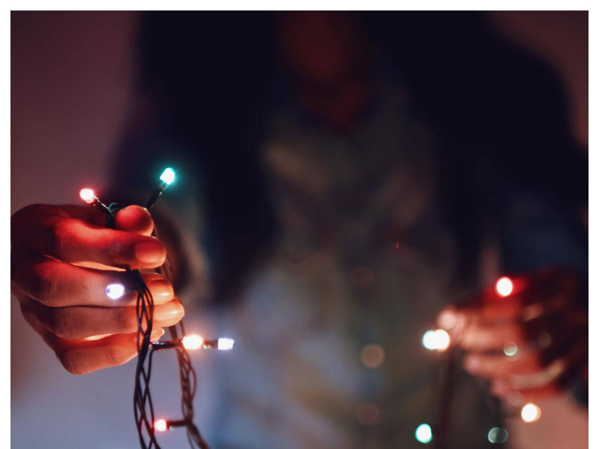 Fairy Lights Aesthetic 桌布 壁紙 — 一個人的雙手輕輕捧著發光的彩色燈串，背景柔和模糊。