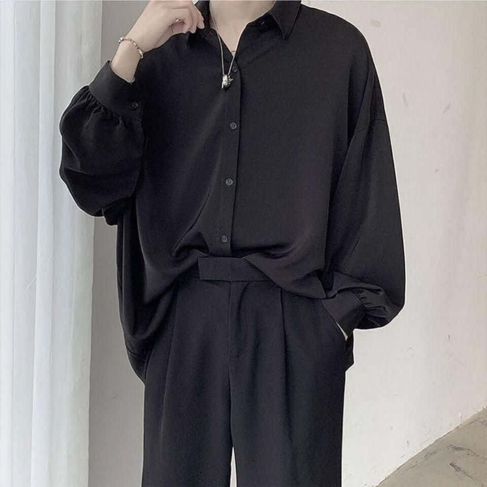 Black Clothing 桌布 壁紙 — 一個人穿著一件超大黑色鈕扣襯衫和配套褲子，站在白色窗簾附近，一隻手放在脖子旁邊。