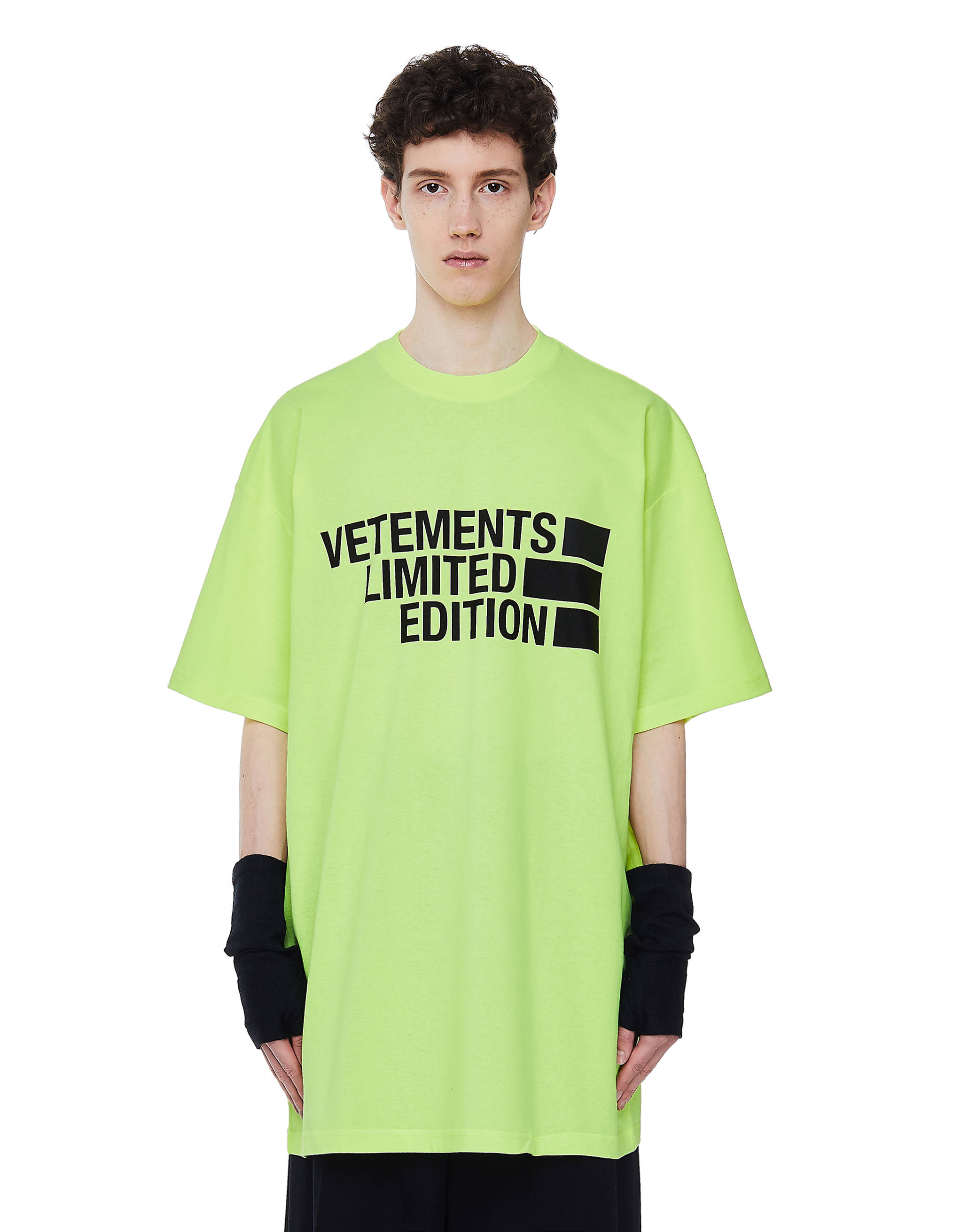 Vetements 桌布 壁紙 — 一個人穿著一件鮮豔的螢光綠色超大T恤，上面有粗體黑色「VETEMENTS LIMITED EDITION」文字，背景為純白色。