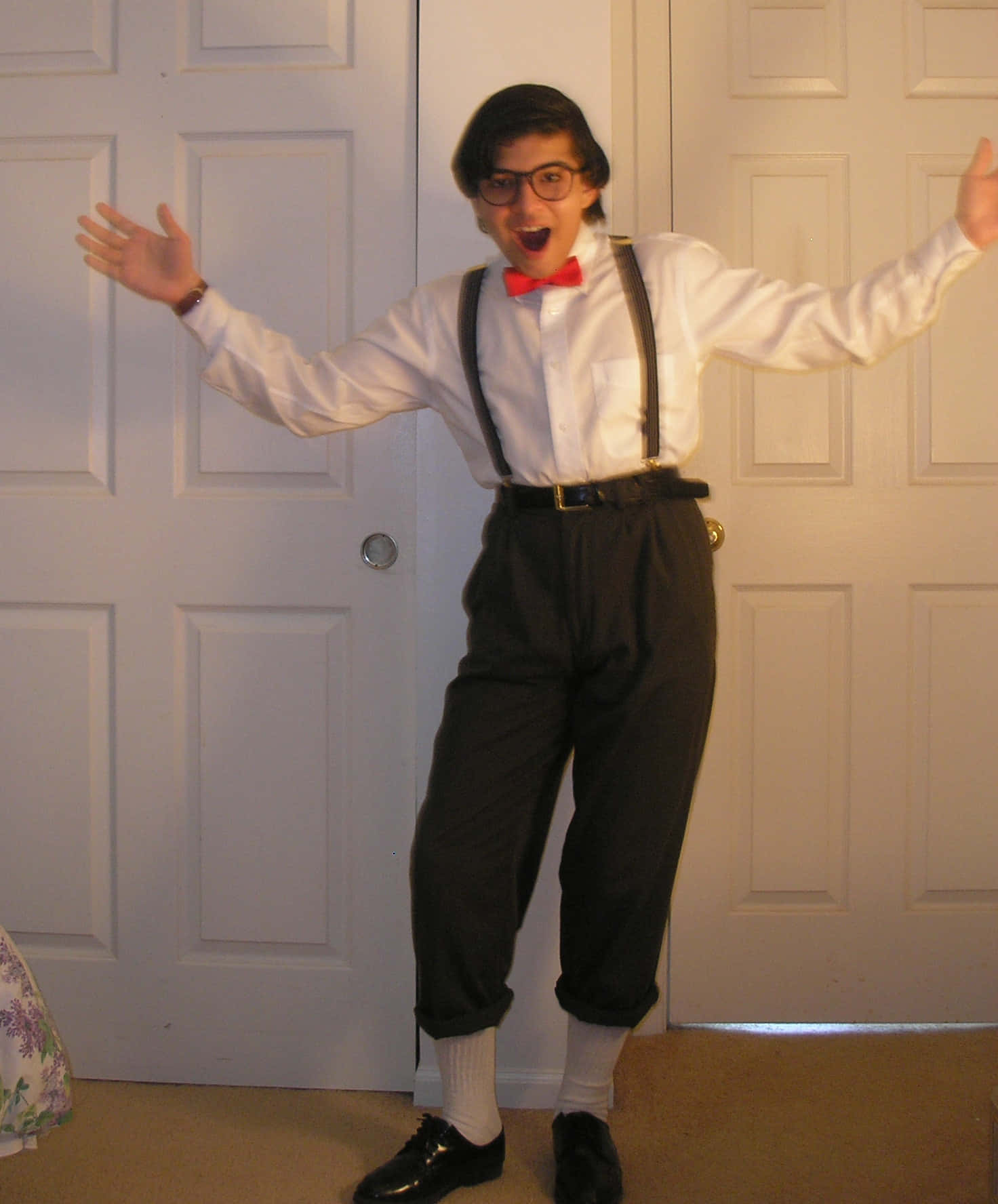 Nerd 桌布 壁紙 — 一個人穿著復古80年代服裝，配有吊帶和紅色領結，在白色門前興奮地擺姿勢。