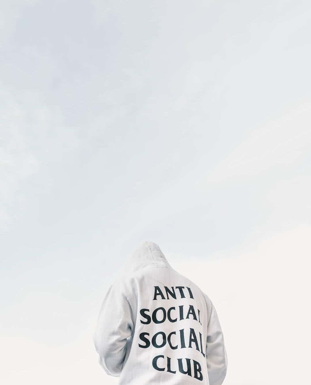 Anti Social Club iPhone 桌布 壁紙 — 一個人穿著白色連帽衫，上面有「ANTI SOCIAL SOCIAL CLUB」字樣，背對鏡頭站在蒼白的天空下。