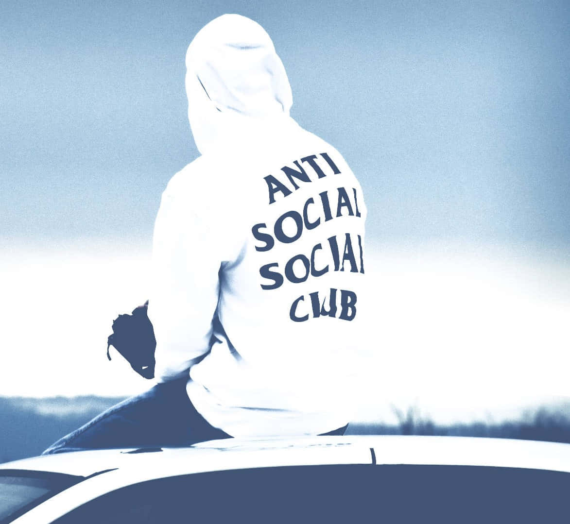 Anti Social Club iPhone 桌布 壁紙 — 一個人穿著白色連帽衫，上面有'ANTI SOCIAL SOCIAL CLUB'字樣，坐在一輛車的車頂上，背景是朦朧的藍天。