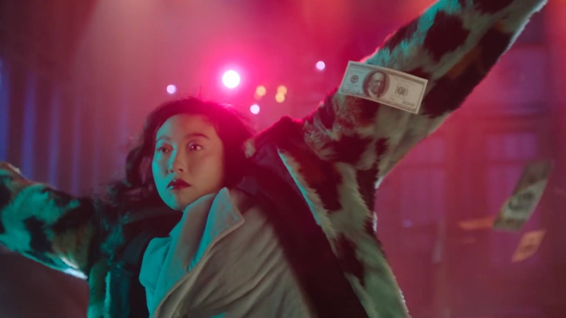 Awkwafina 桌布 壁紙 — 一個人穿著豹紋外套，在充滿活力的紅色和藍色舞台燈光下將錢拋向空中。