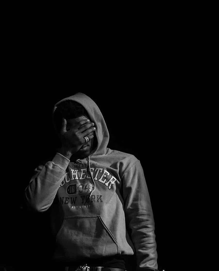 Depressed 桌布 壁紙 — 一個人穿著連帽衫，在純黑背景下用手遮臉，營造出陰鬱的黑白畫面。