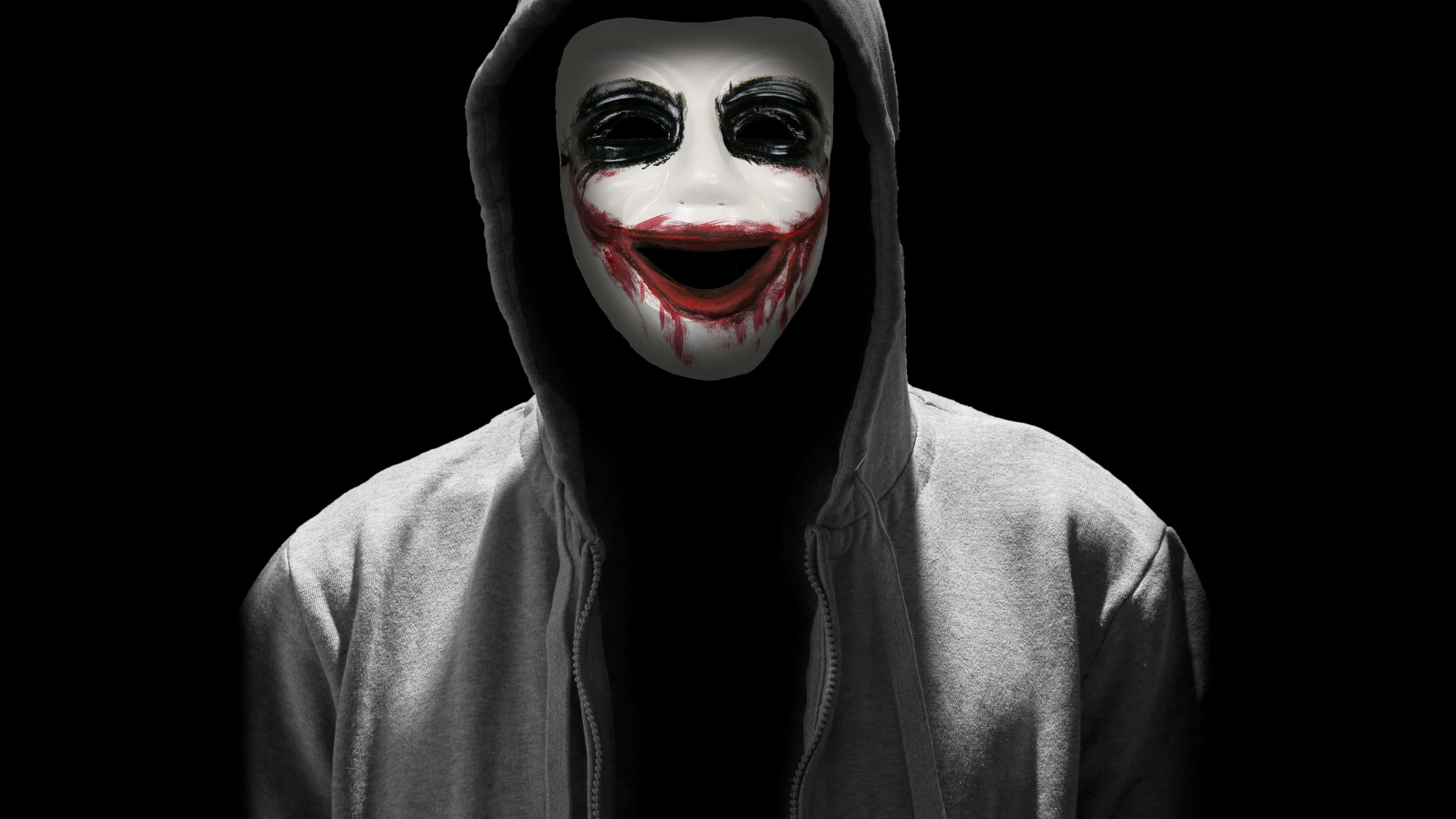 Mask 桌布 壁紙 — 一個人穿著連帽衫，戴著白色面具，面具上有黑色眼睛和紅色滴落的微笑，背景為黑色。