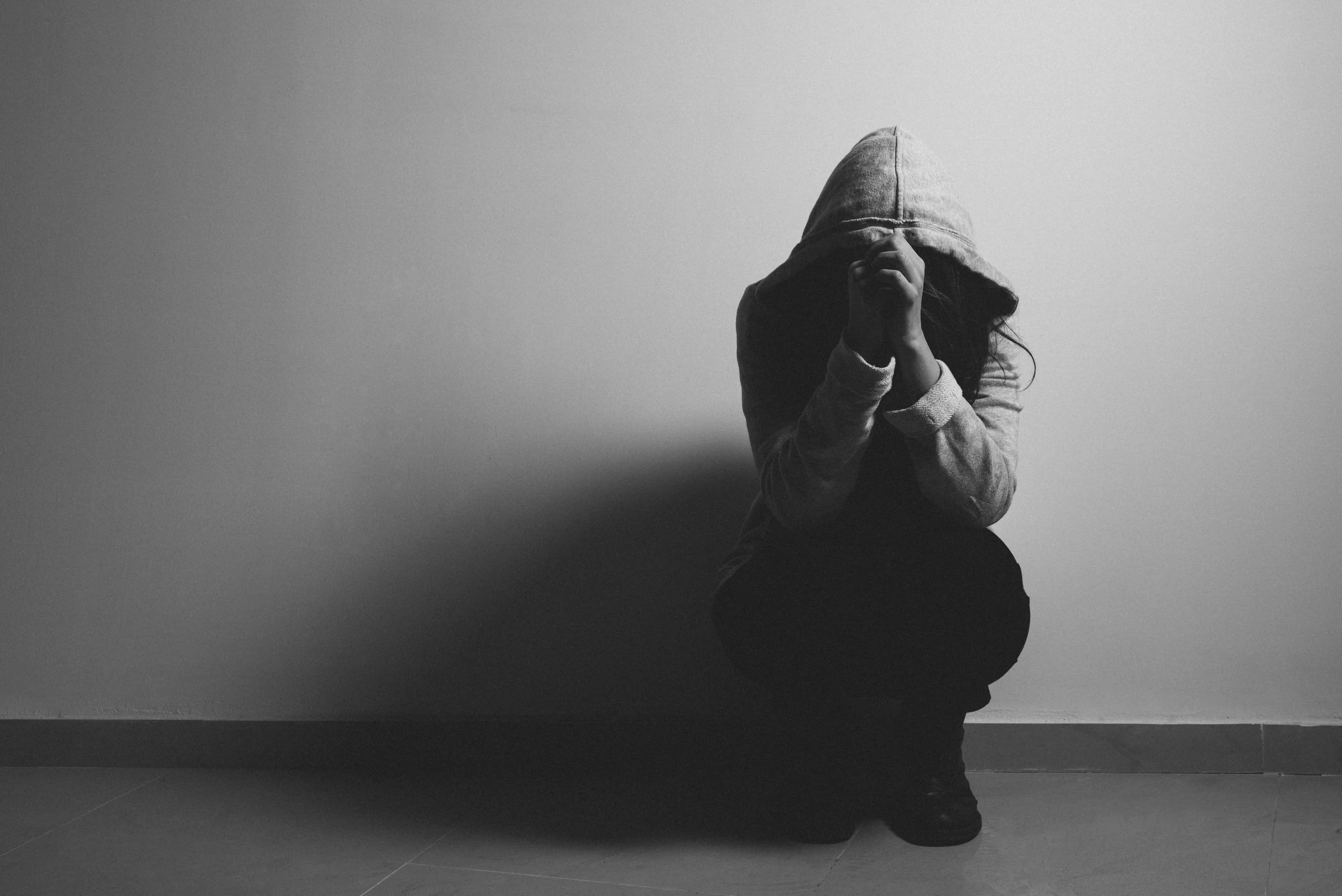 Depressed 桌布 壁紙 — 一個人穿著連帽衫蹲在瓷磚地板上，雙手遮臉，在一個黑白分明的房間裡。