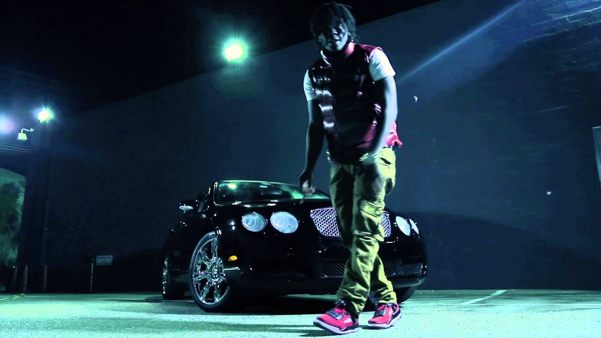 Chief Keef 桌布 壁紙 — 一個人穿著鮮豔的粉紅色運動鞋，在夜晚刺眼的綠色舞台燈光下自信地站在時尚的黑色賓利旁邊。