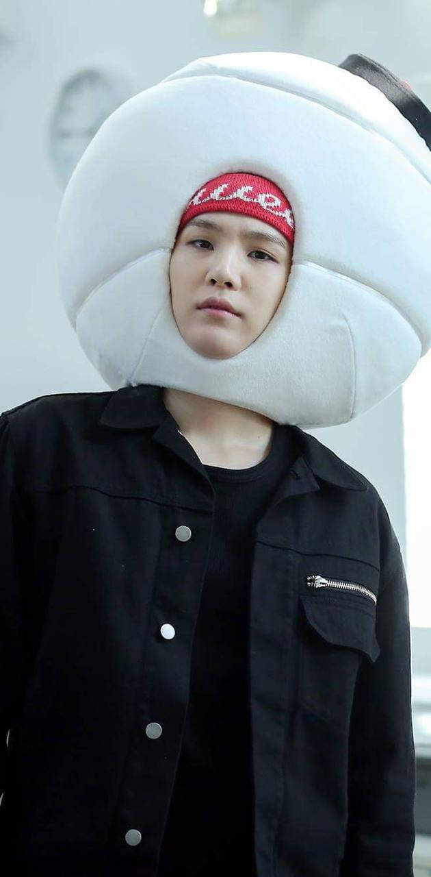 BTS 鎖定螢幕 桌布 壁紙 — 一個人穿著黑色衣服，戴著一個巨大的白色餃子形狀的頭枕，下面戴著紅色無邊帽。