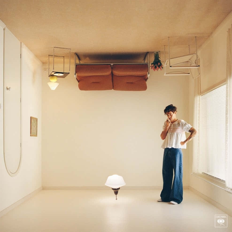 Harry Styles Album Cover 桌布 壁紙 — 一個人站在一個極簡風格的房間裡，房間內有一盞漂浮的燈和倒置的家具，營造出超現實的反重力藝術。