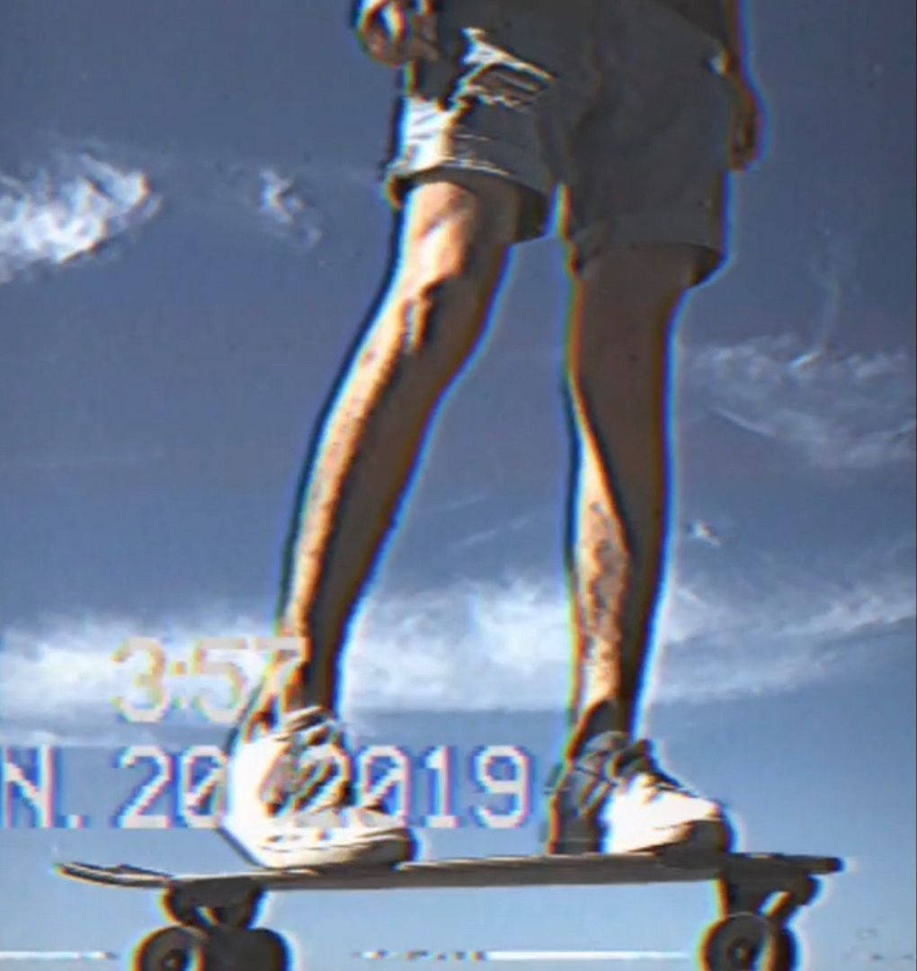 skate 桌布 壁紙 — 一個人站在滑板上，背景是帶有故障效果的藍天白雲和數位疊加文字。