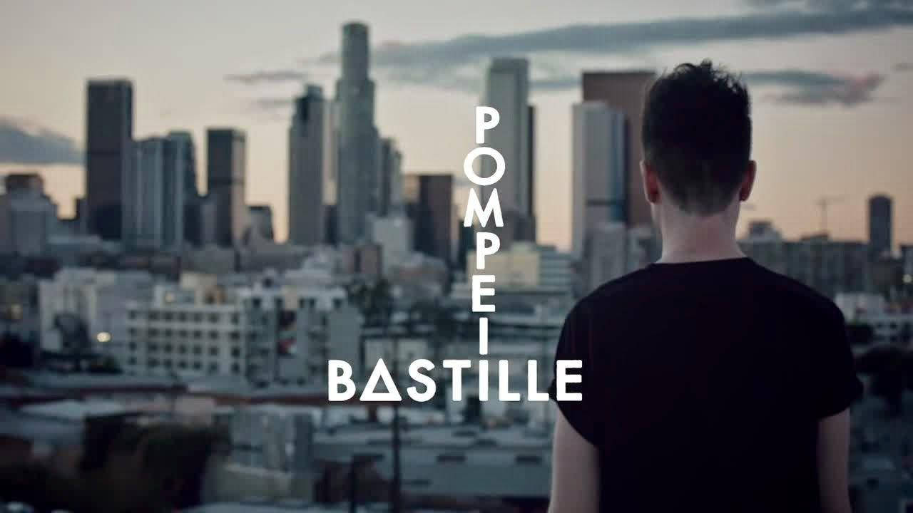Bastille 桌布 壁紙 — 一個人背對相機，俯瞰黃昏時分廣闊的城市天際線，並帶有文字疊加。