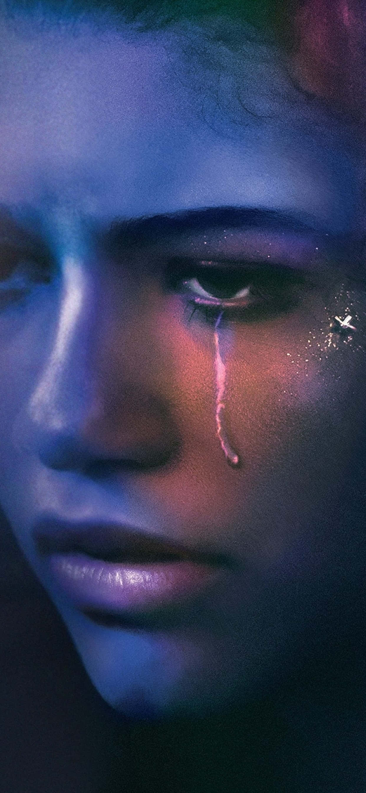 Euphoria Hbo iPhone 桌布 壁紙 — 一個人臉部的特寫肖像，被霓虹藍和粉紅光照亮，一顆發光的淚珠沿著臉頰滑落。