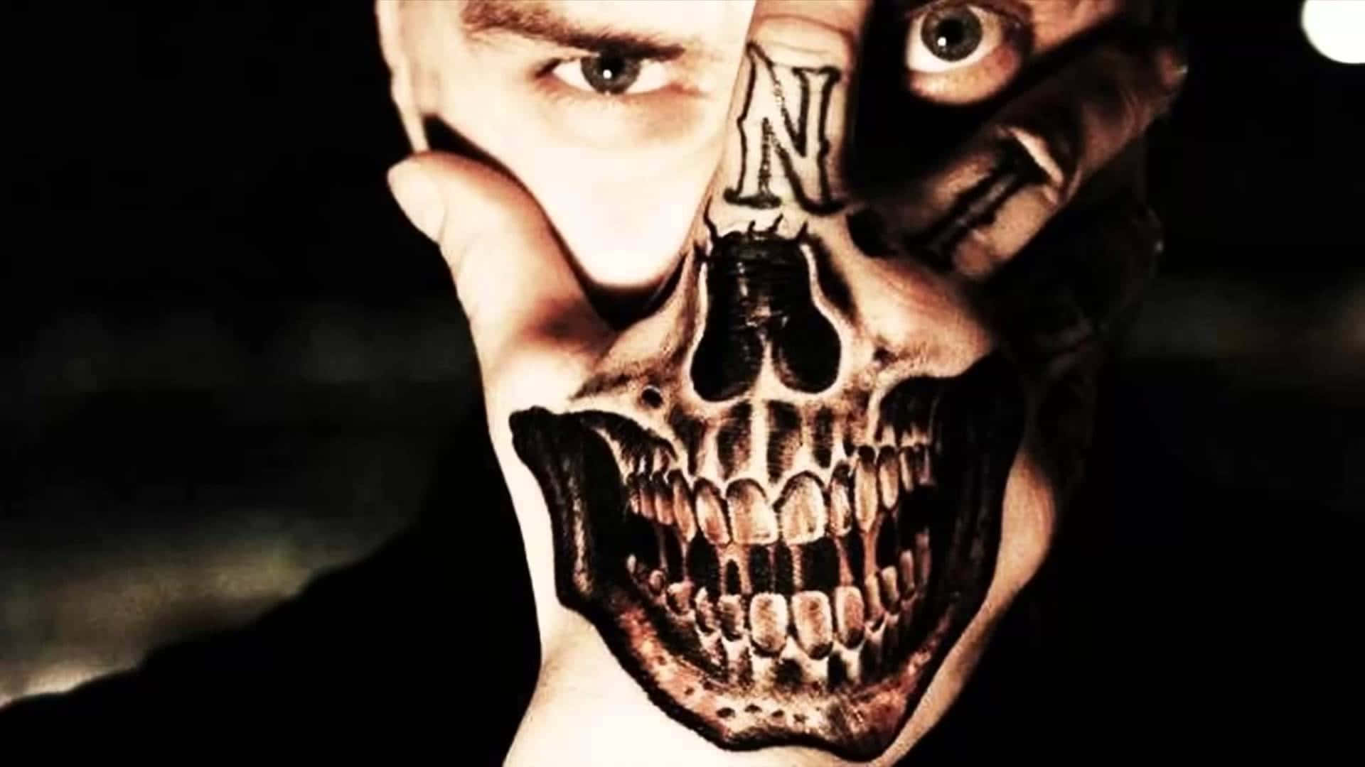 Halloween Tattoos 桌布 壁紙 — 一個人舉起一隻手，手掌和手指上覆蓋著精細的骷髏刺青，在黑暗背景下露出一隻眼睛和部分臉龐。