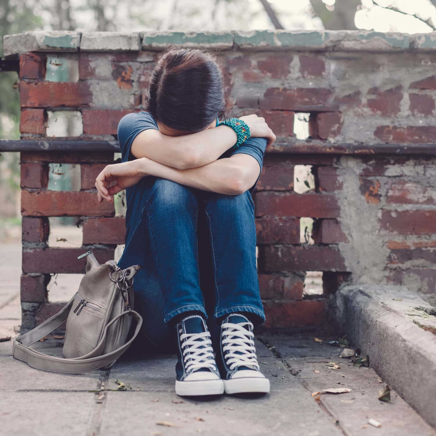 Depressed 桌布 壁紙 — 一個人蜷縮在風化的磚牆上，雙手抱住膝蓋，旁邊有個背包，在寧靜的孤獨時刻。