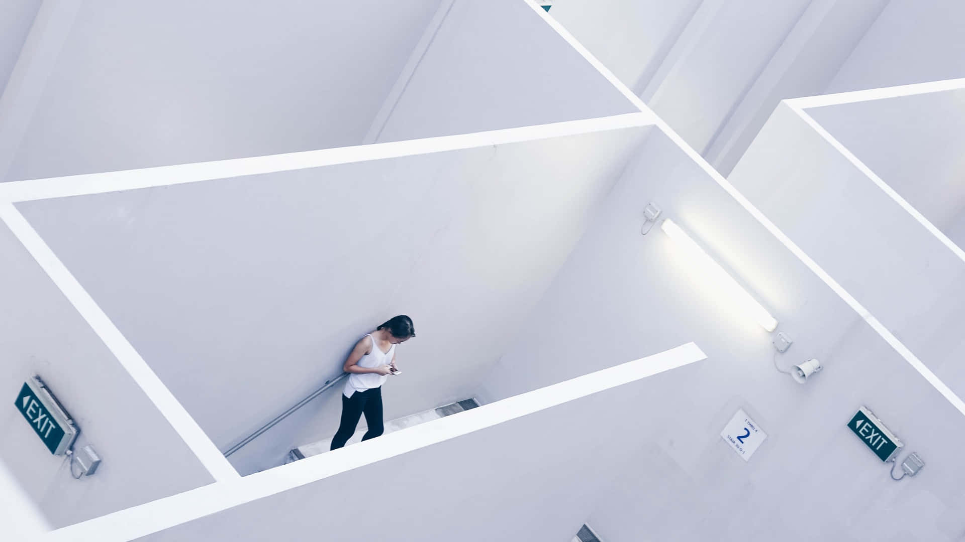 catatonic 桌布 壁紙 — 一個人走在由螢光燈和出口標誌照亮的簡潔白色幾何走廊上。
