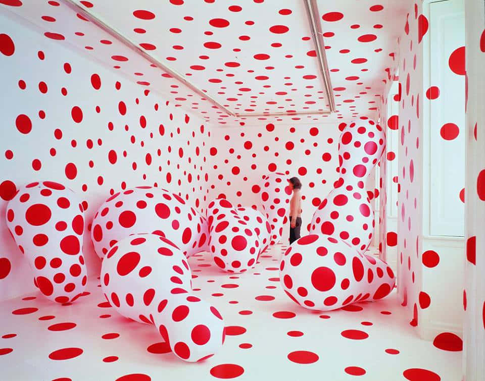Installation Art 桌布 壁紙 — 一個人走過一個超現實的白色房間，裡面充滿了巨大的紅色圓點充氣雕塑和牆壁。