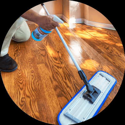 Wooden Floor 桌布 壁紙 — 一個人跪著用藍色拖把和噴霧瓶清潔光亮的硬木地板，房間光線溫暖。