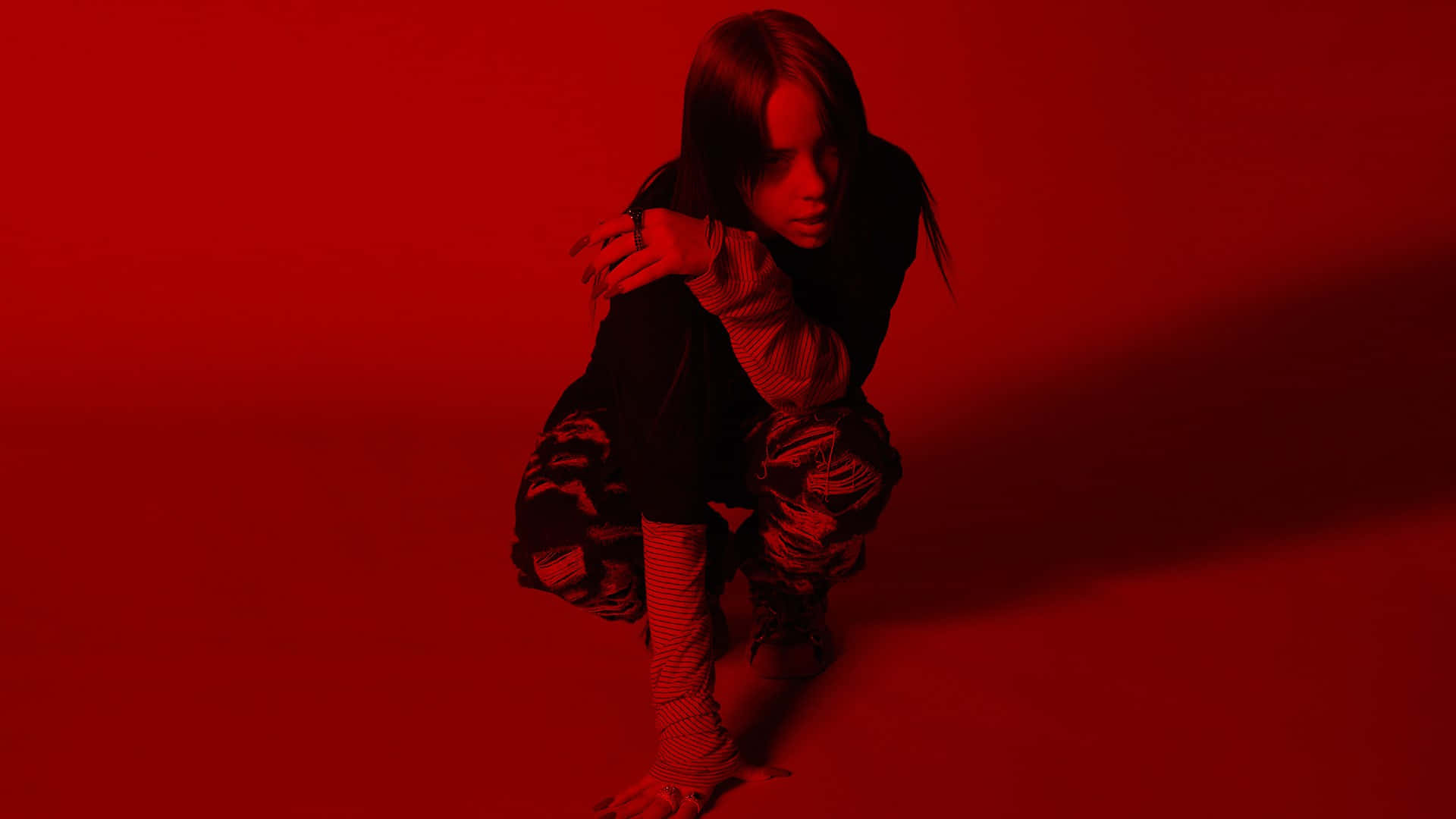 Billie Eilish Laptop 桌布 壁紙 — 一個人蹲在單色調的紅色攝影棚中，戲劇性的燈光投射出長長的影子。