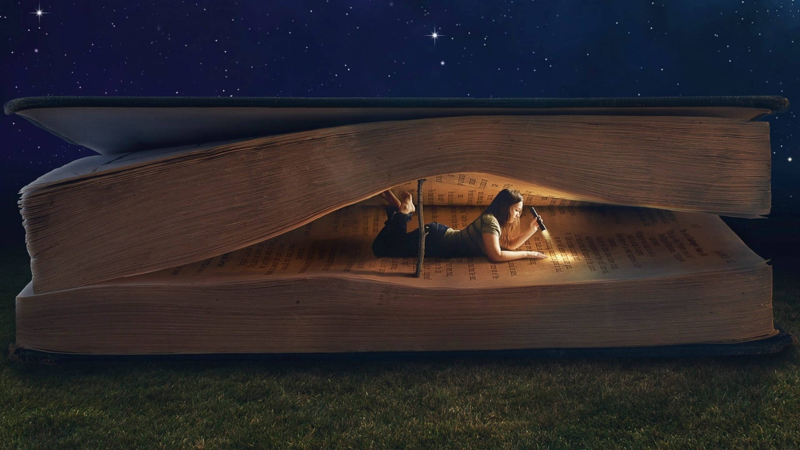 Reading 桌布 壁紙 — 一個人躺在草地上，在星空下的一本巨大打開的書裡閱讀。