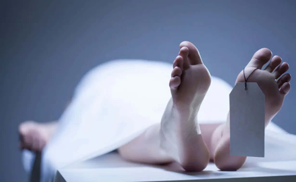 死亡 桌布 壁紙 — 一個人躺著，被白色床單覆蓋，露出赤腳，一隻腳上繫著空白標籤，背景為灰色。