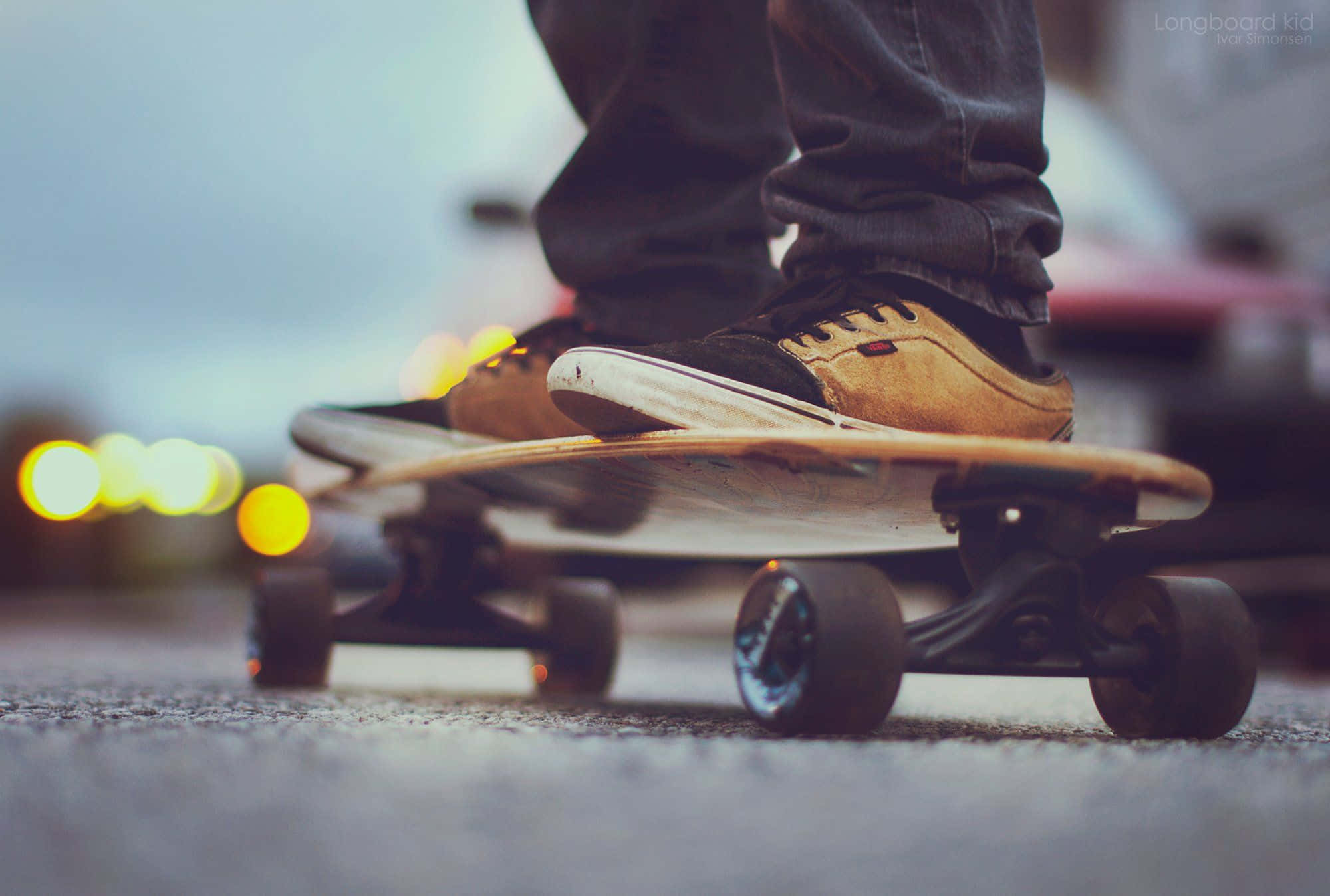 Retro Skateboard 桌布 壁紙 — 一個人雙腳踩在長板上的特寫，背景有模糊的城市燈光閃爍。