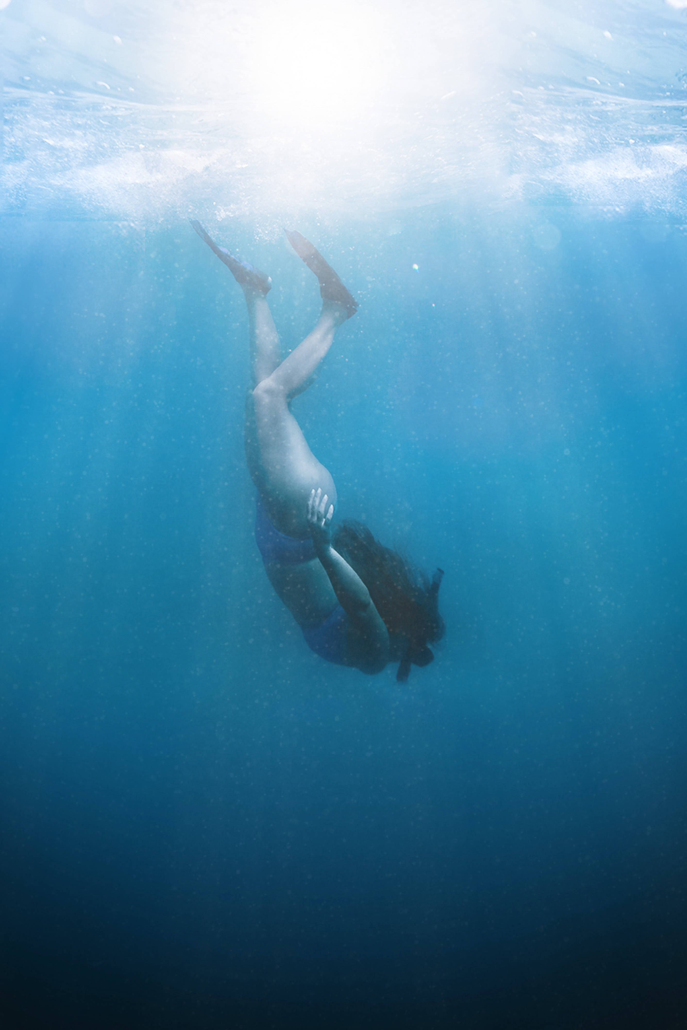 Snorkeling 桌布 壁紙 — 一個人頭朝下潛入清澈的藍色海水，陽光從上方照射下來。