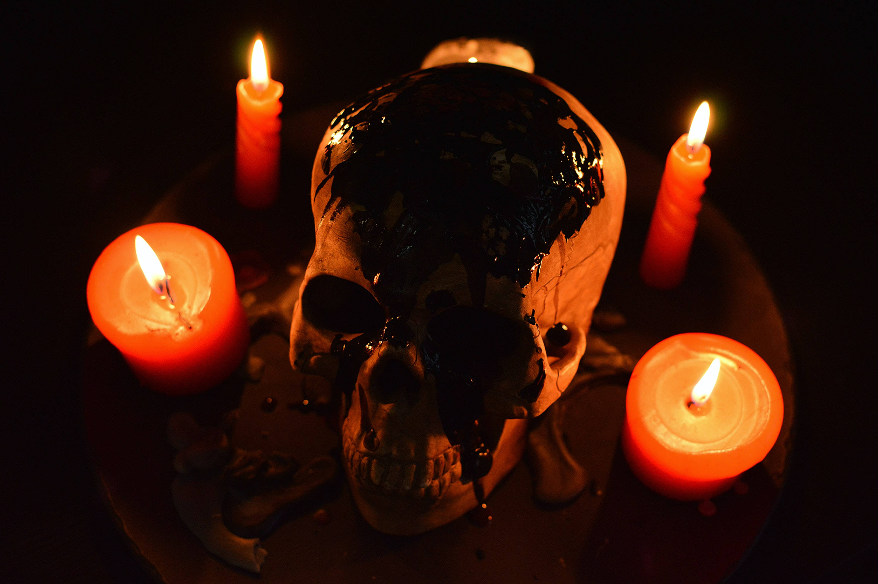 skulls 桌布 壁紙 — 一個人類頭骨，黑色液體從臉上滴下，被黑暗中的四根紅色蠟燭環繞。